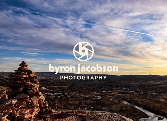 An aerial view of a Wyoming townscape from a large hill with artistic rock pile on it—oh, and the logo