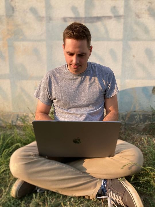 Me, sitting cross-legged in an alleyway looking pensively at my laptop